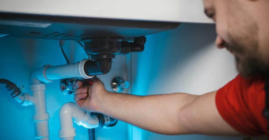 Plumber working on pipework in a wall
